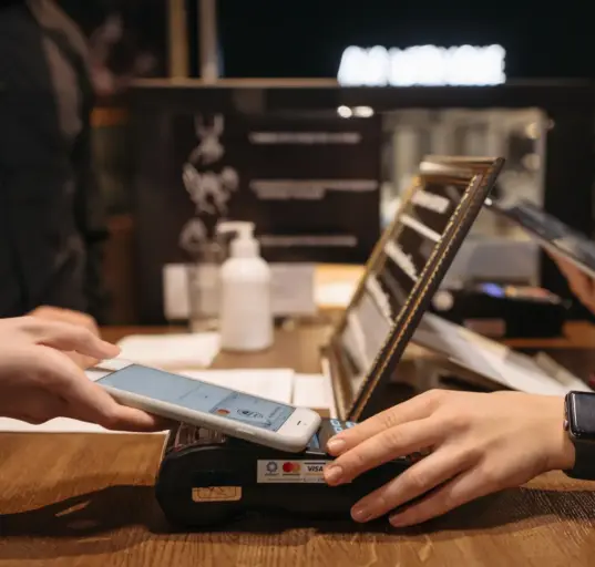 Kundin bezahlt mit einem Smartphone an einem Kartenterminal