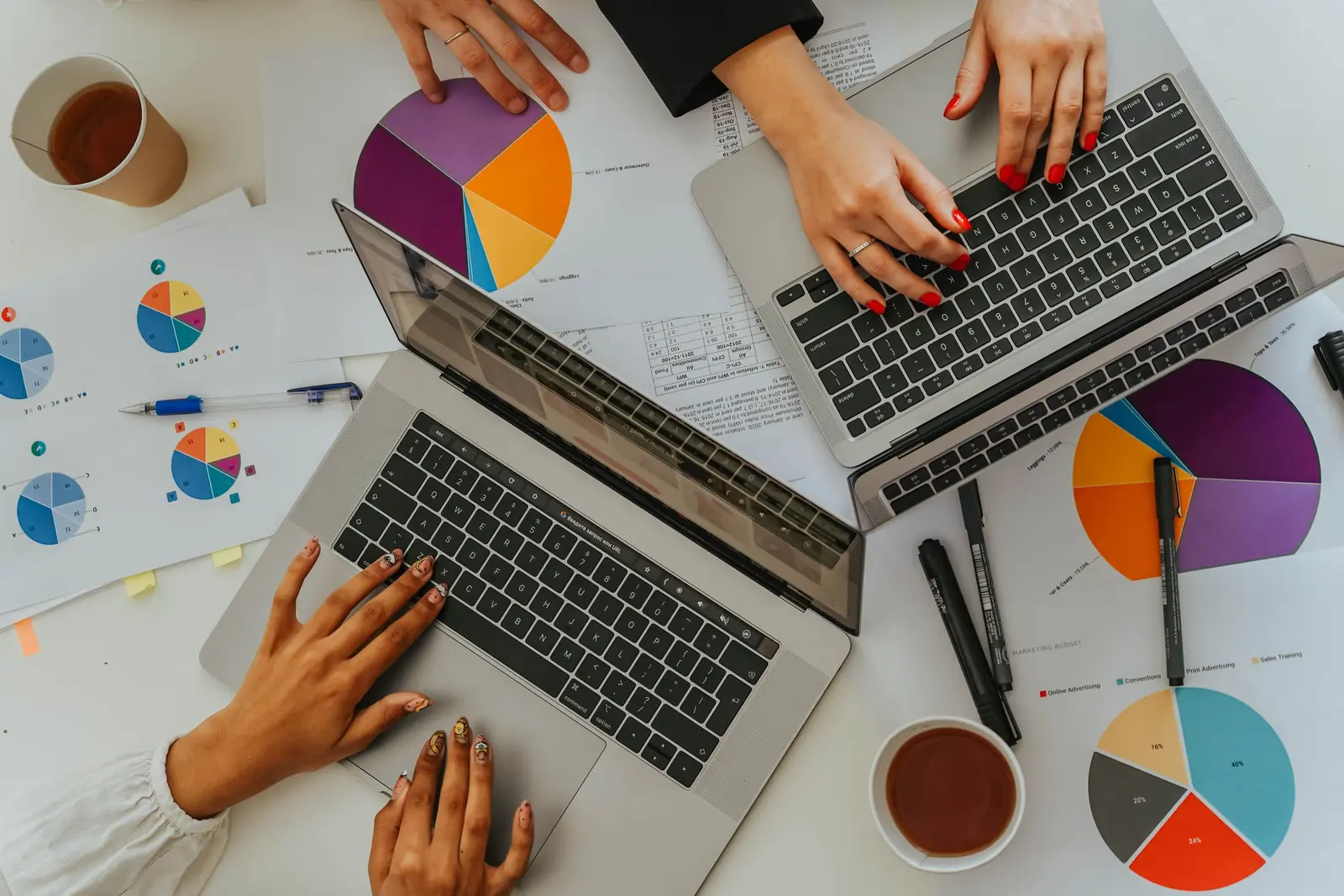 Team prüft Diagramme und Geschäftsdaten an mehreren Laptops