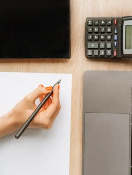 Schreibtisch mit Laptop, Taschenrechner und Unterlagen zur digitalen Buchhaltung
