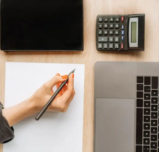 Schreibtisch mit Laptop, Taschenrechner und Unterlagen zur digitalen Buchhaltung