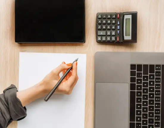 Schreibtisch mit Laptop, Taschenrechner und Unterlagen zur digitalen Buchhaltung