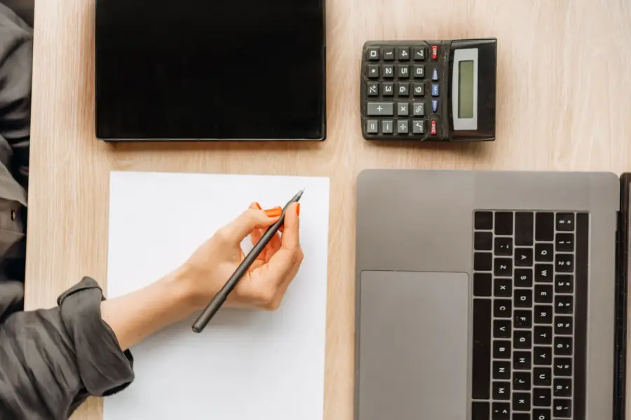 Schreibtisch mit Laptop, Taschenrechner und Unterlagen zur digitalen Buchhaltung