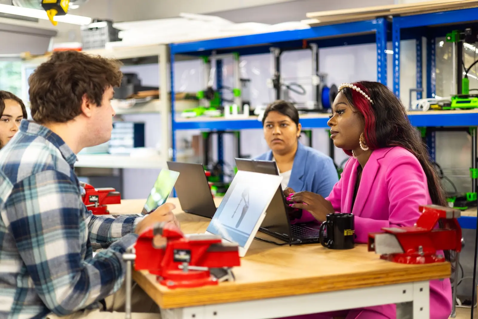 Multikulturelles Technikteam bespricht ein Projekt in einer Werkstatt