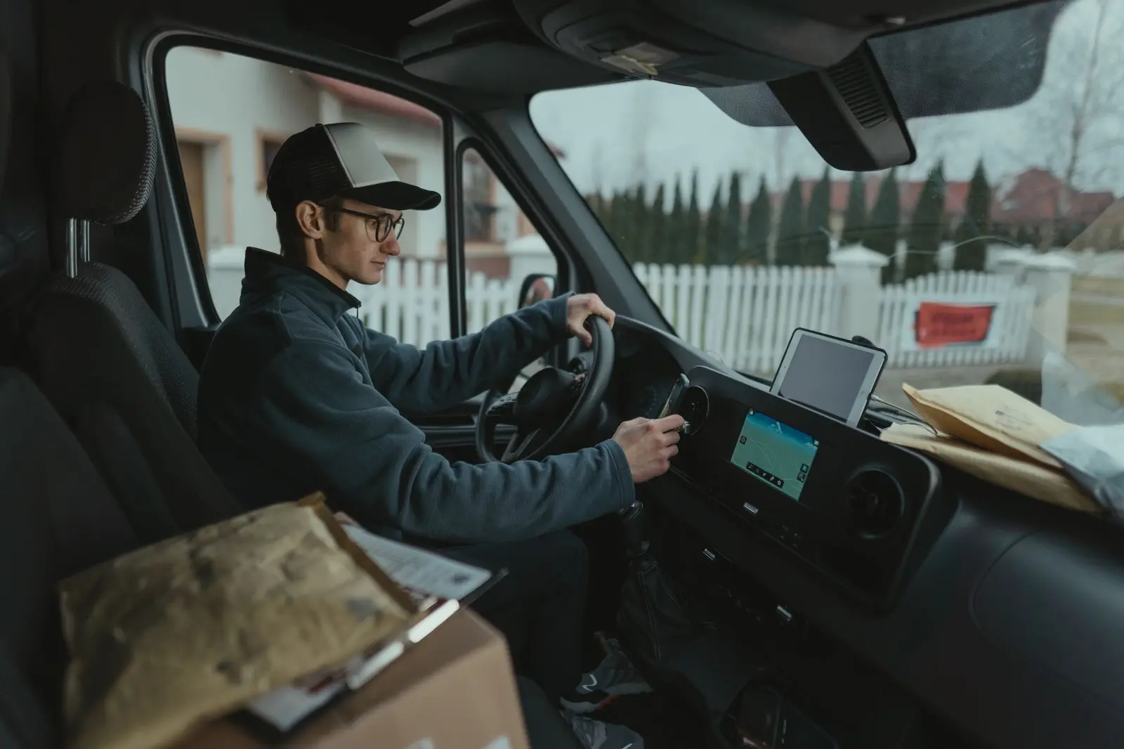 Fahrer eines Lieferdienstes sitzt mit Paketen in einem Transporter