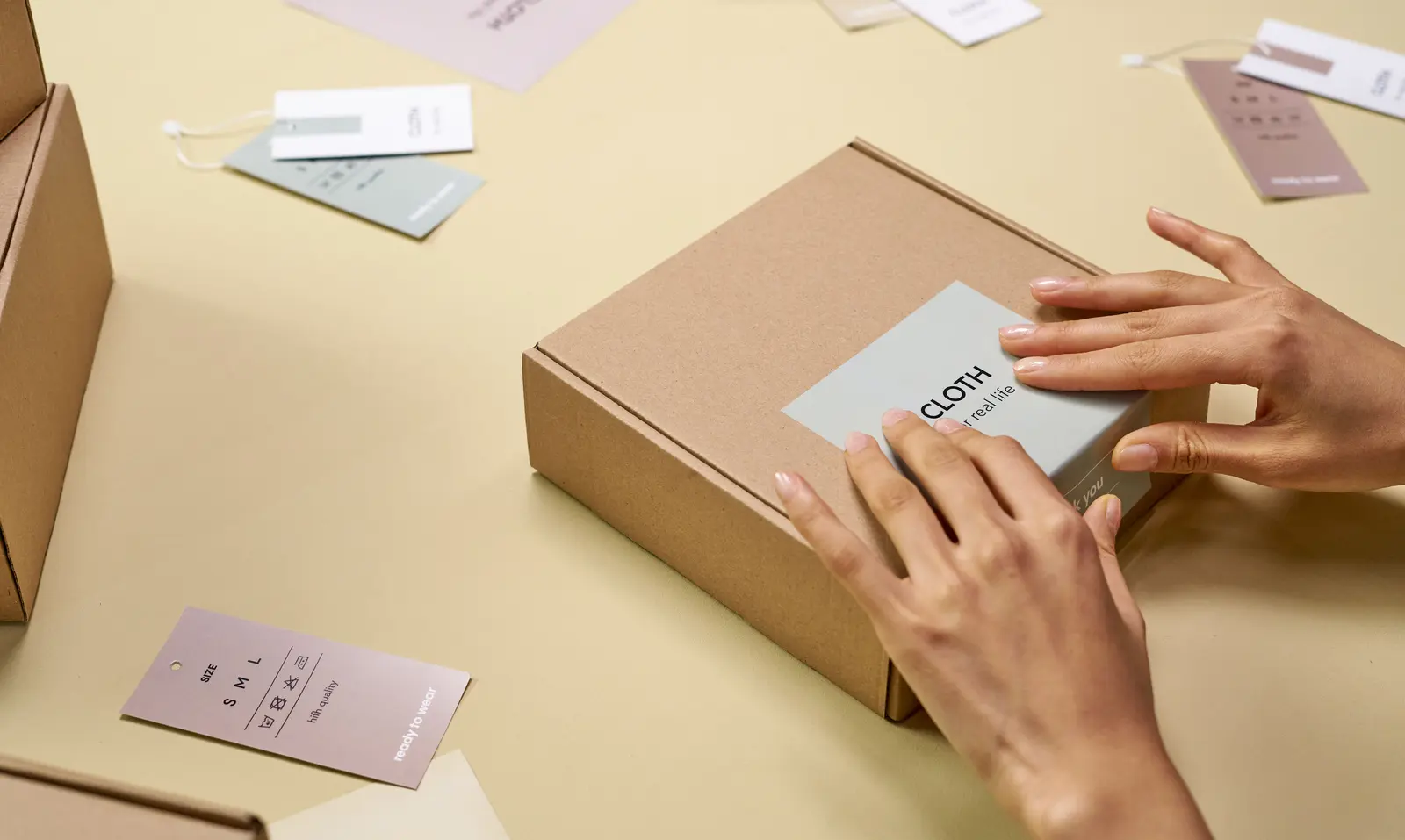 Hände bringen ein Etikett auf einer Produktverpackung an