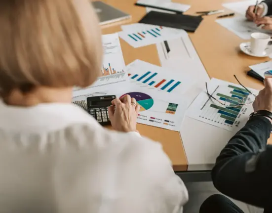 Geschäftsleute prüfen Finanzgrafiken und Berechnungen an einem Tisch