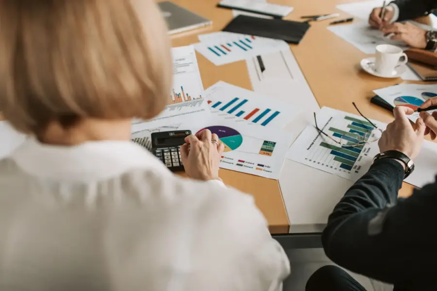 Geschäftsleute prüfen Finanzgrafiken und Berechnungen an einem Tisch
