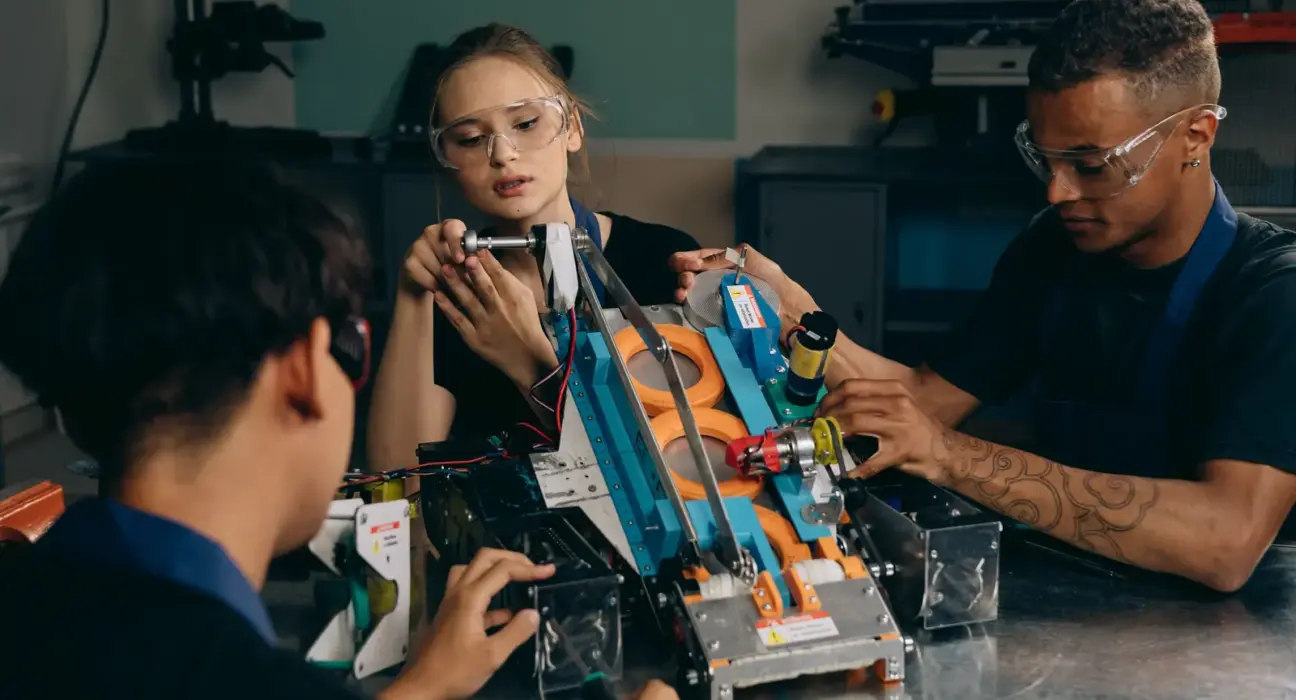 Drei Fachkräfte montieren gemeinsam einen Robotikprototyp in einer Werkstatt