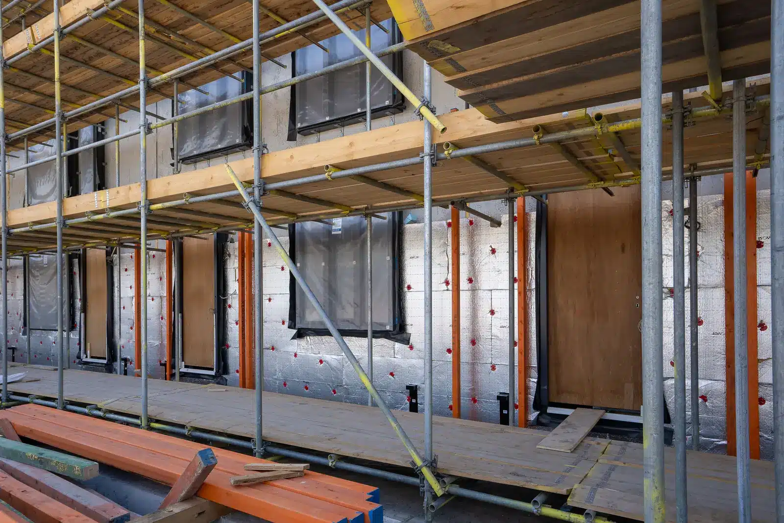 Eingerüstetes Gebäude mit sichtbarer Fassadendämmung und vorbereiteten Fensteröffnungen