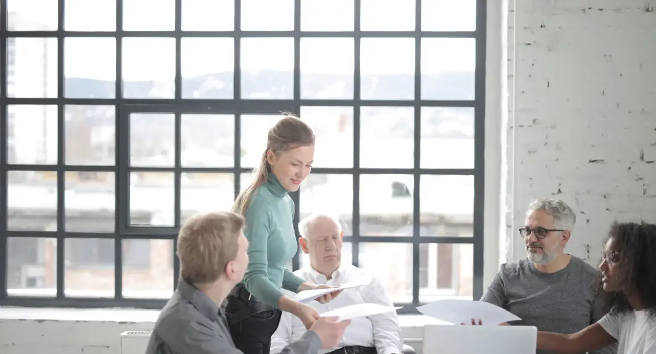 Älterer Mitarbeiter bespricht Unterlagen mit einem altersgemischten Team im Büro