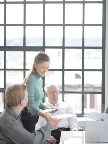 Älterer Mitarbeiter bespricht Unterlagen mit einem altersgemischten Team im Büro