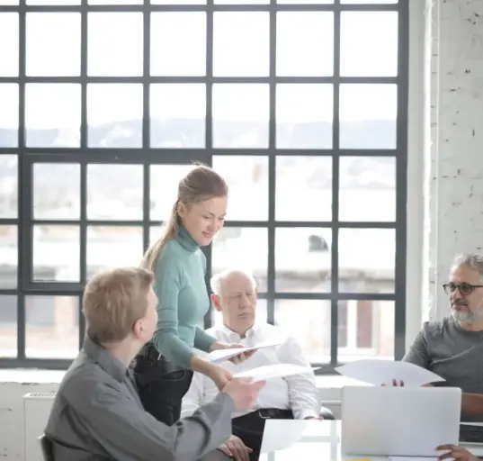 Älterer Mitarbeiter bespricht Unterlagen mit einem altersgemischten Team im Büro