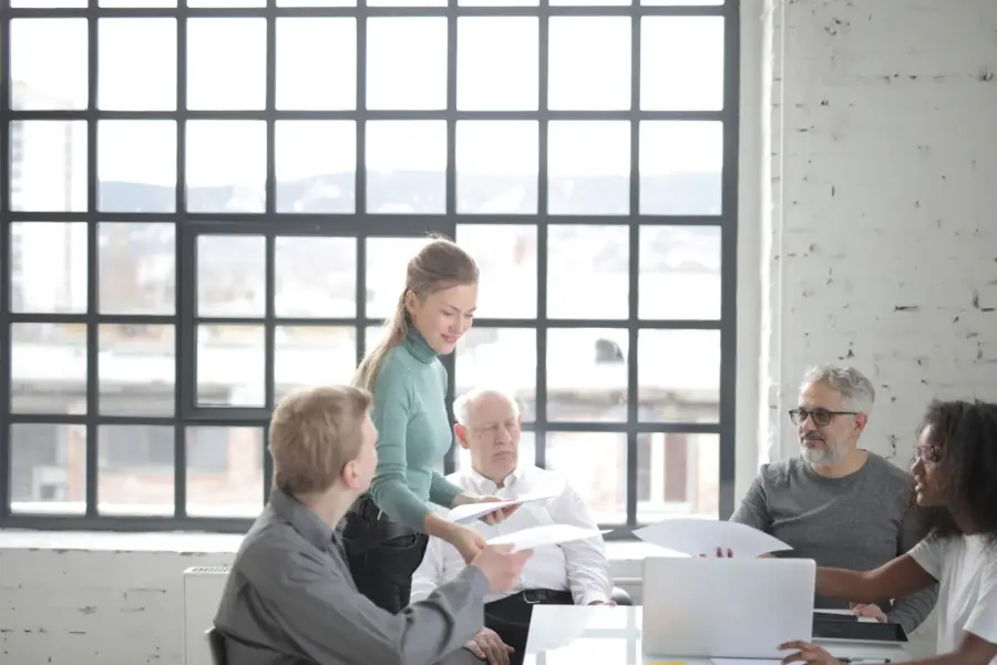 Älterer Mitarbeiter bespricht Unterlagen mit einem altersgemischten Team im Büro