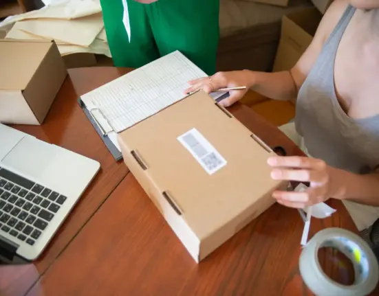 Zwei Mitarbeiterinnen eines kleinen Onlinehandels verpacken Bestellungen in Versandkartons