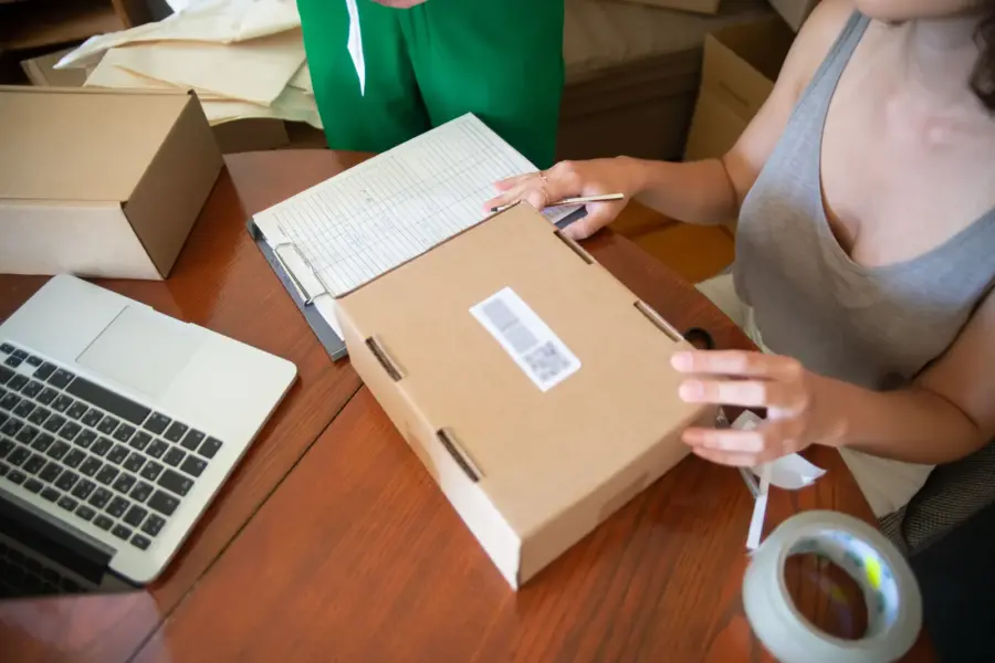 Zwei Mitarbeiterinnen eines kleinen Onlinehandels verpacken Bestellungen in Versandkartons