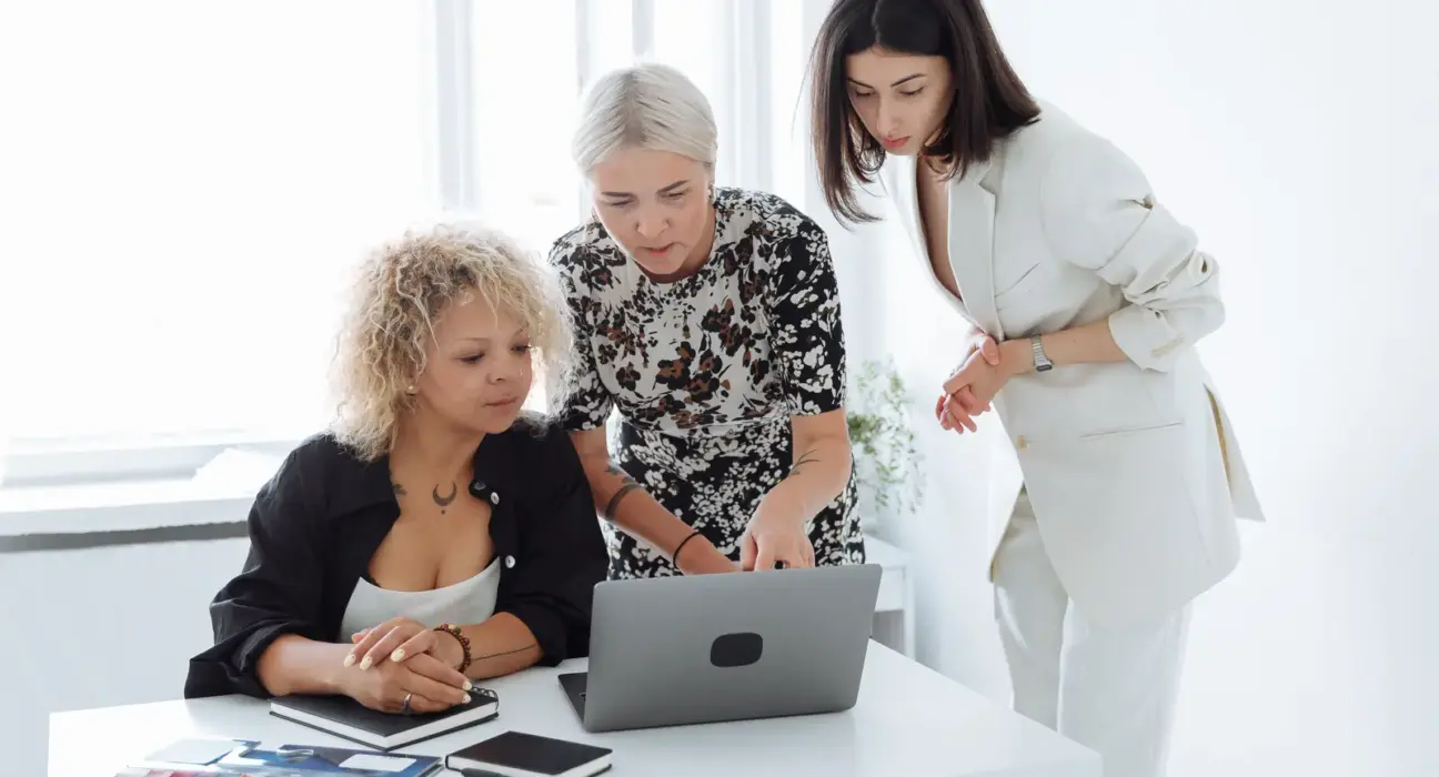Drei Gründerinnen arbeiten gemeinsam an einem Laptop und besprechen eine Geschäftsidee