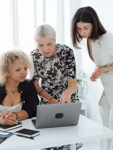 Drei Gründerinnen arbeiten gemeinsam an einem Laptop und besprechen eine Geschäftsidee