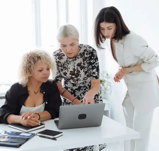 Drei Gründerinnen arbeiten gemeinsam an einem Laptop und besprechen eine Geschäftsidee