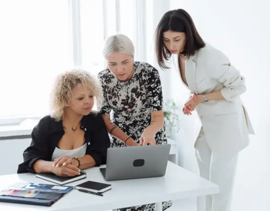 Drei Gründerinnen arbeiten gemeinsam an einem Laptop und besprechen eine Geschäftsidee