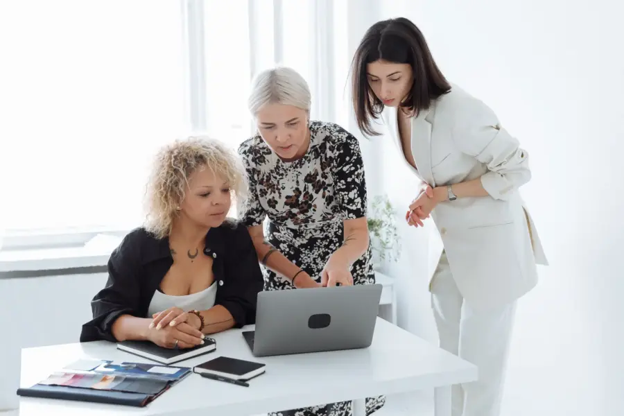 Drei Gründerinnen arbeiten gemeinsam an einem Laptop und besprechen eine Geschäftsidee