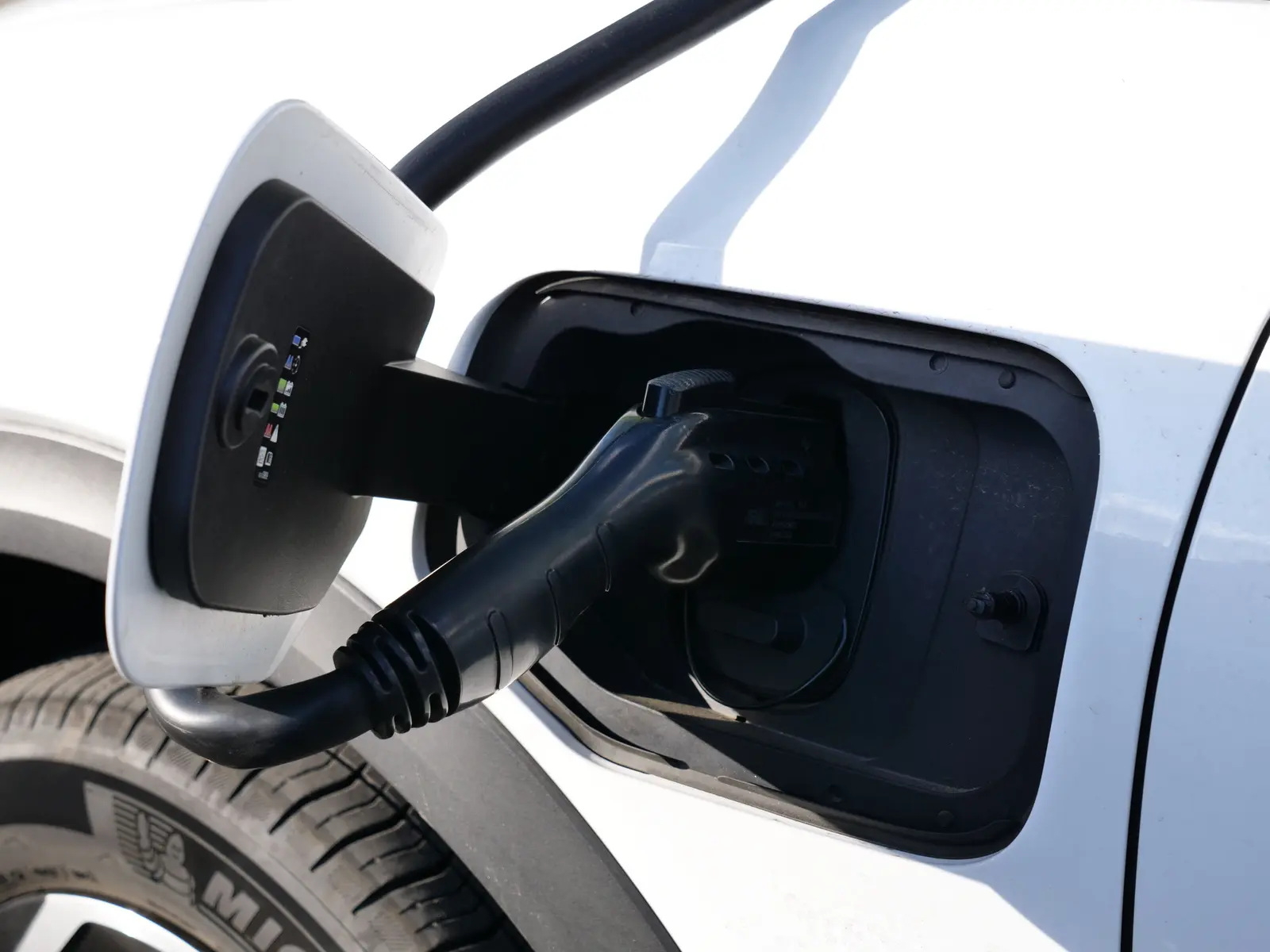 Ladestecker steckt im Ladeanschluss eines weißen Elektrofahrzeugs