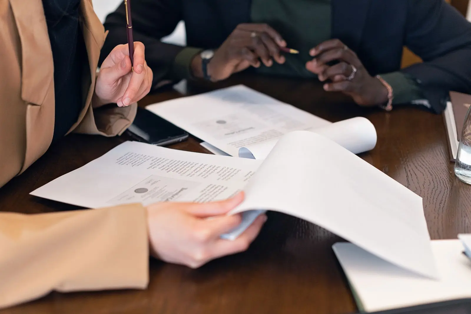 Drei Personen prüfen gemeinsam Unterlagen bei einem Finanzierungsgespräch