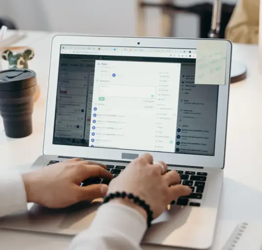 Person arbeitet in einem hellen Büro an einem Laptop