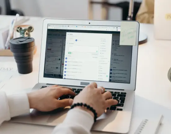 Person arbeitet in einem hellen Büro an einem Laptop