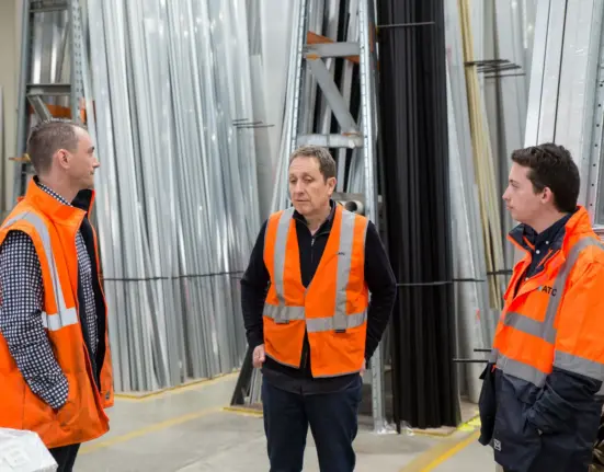 Drei Beschäftigte besprechen die Arbeitsplanung in einer Produktionshalle