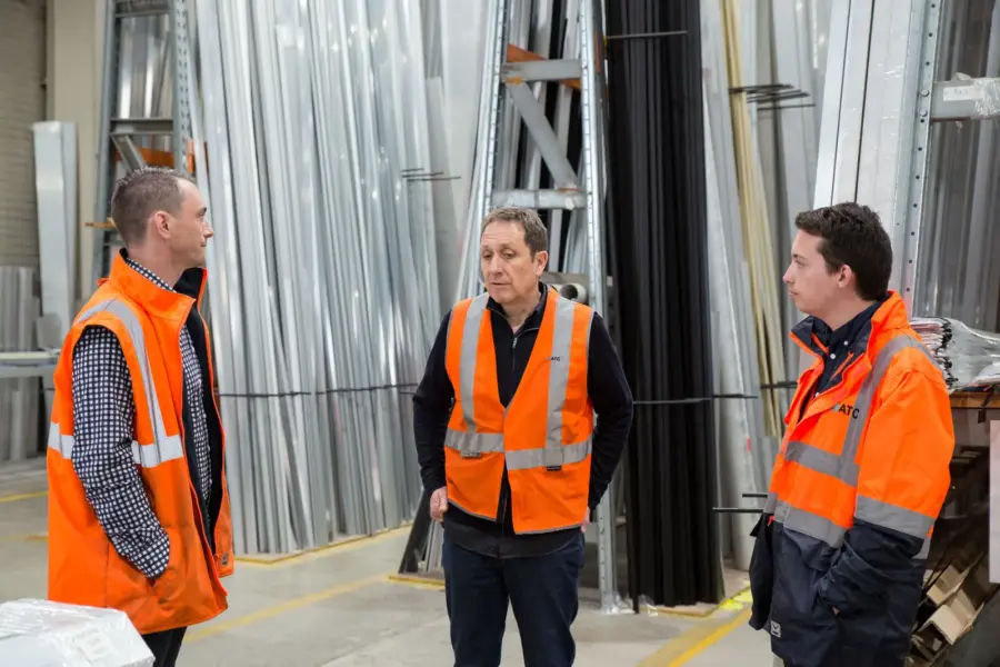 Drei Beschäftigte besprechen die Arbeitsplanung in einer Produktionshalle