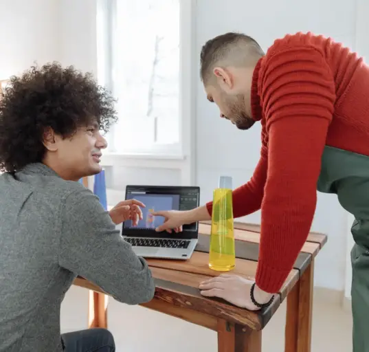 Zwei Mitarbeiter eines kleinen Betriebs besprechen am Laptop ein digitales Produktmodell