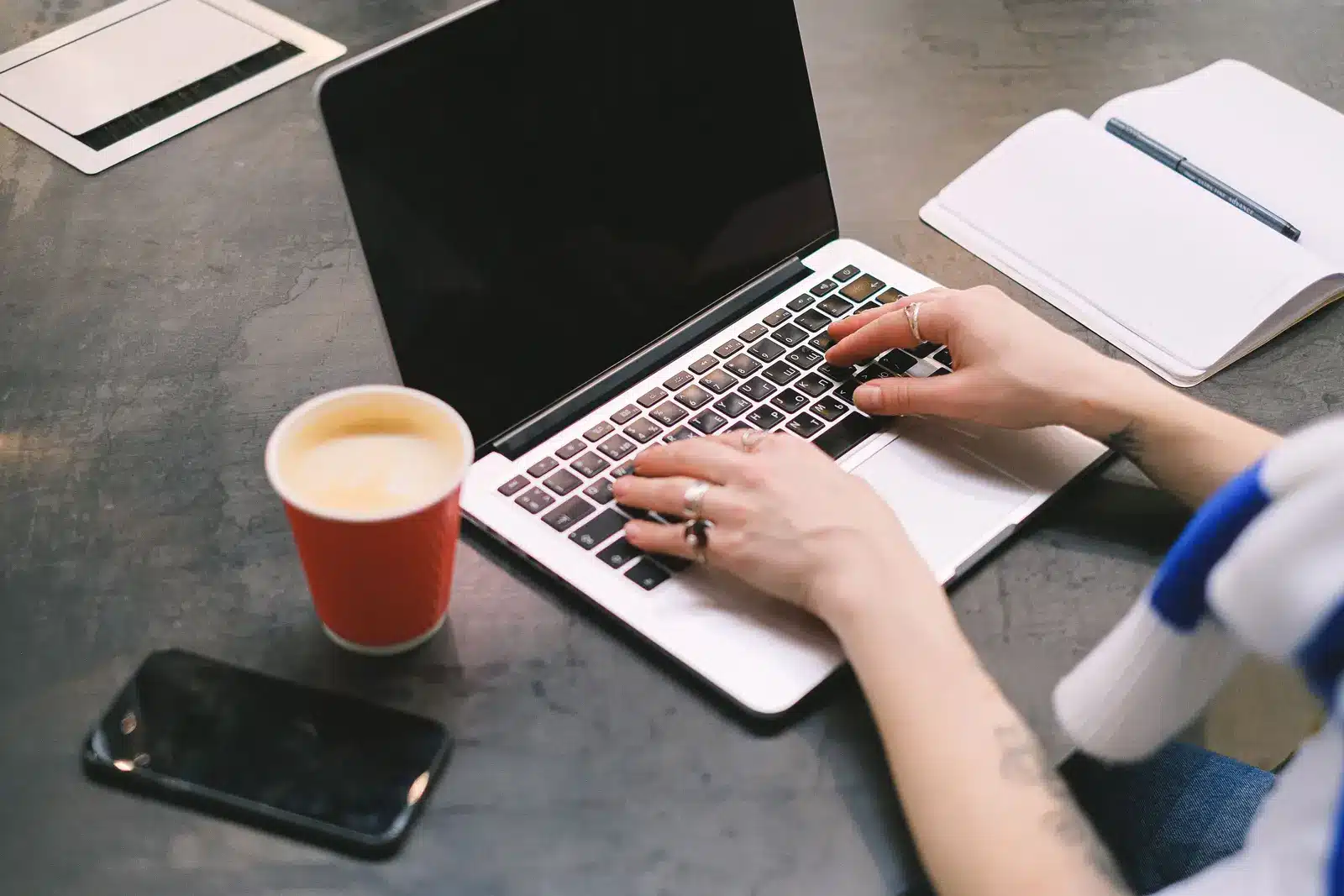 Hände einer selbstständigen Person beim Arbeiten an einem Laptop
