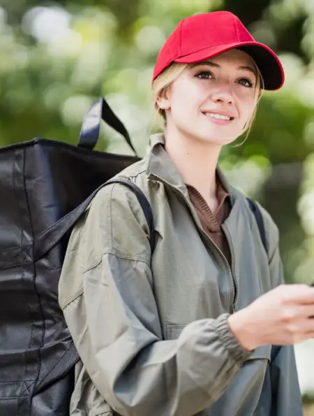 Kurierin mit Lieferucksack hält bei der Arbeit ein Smartphone in der Hand