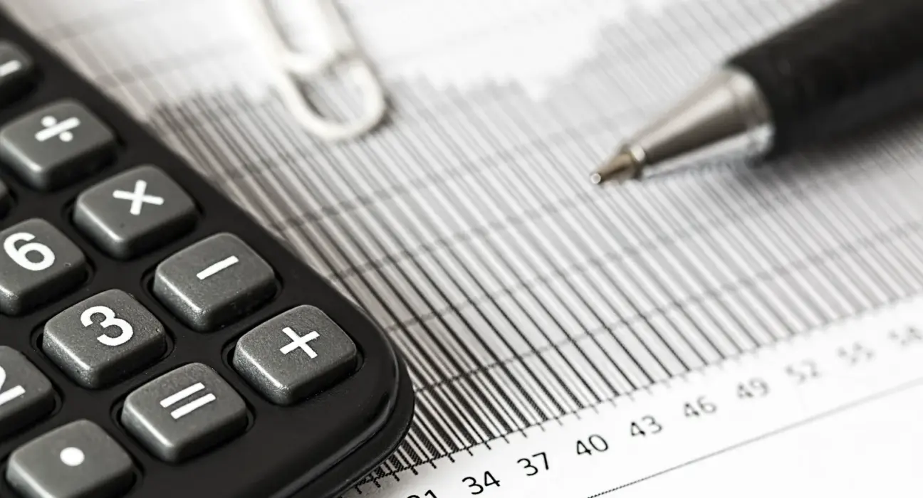 Taschenrechner und Stift liegen auf einer gedruckten Finanzübersicht
