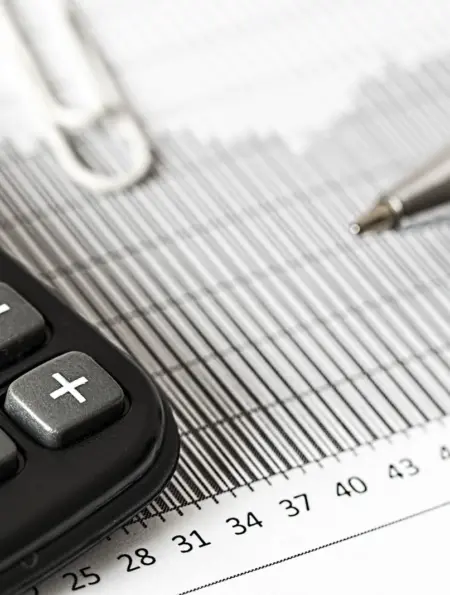 Taschenrechner und Stift liegen auf einer gedruckten Finanzübersicht