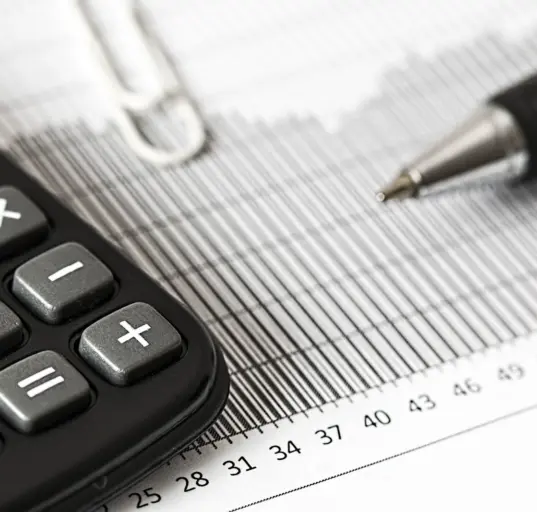 Taschenrechner und Stift liegen auf einer gedruckten Finanzübersicht