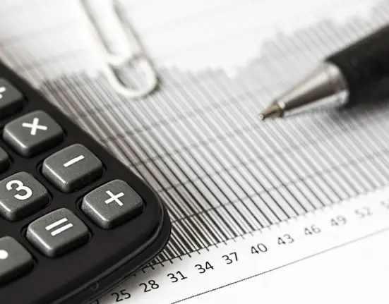 Taschenrechner und Stift liegen auf einer gedruckten Finanzübersicht