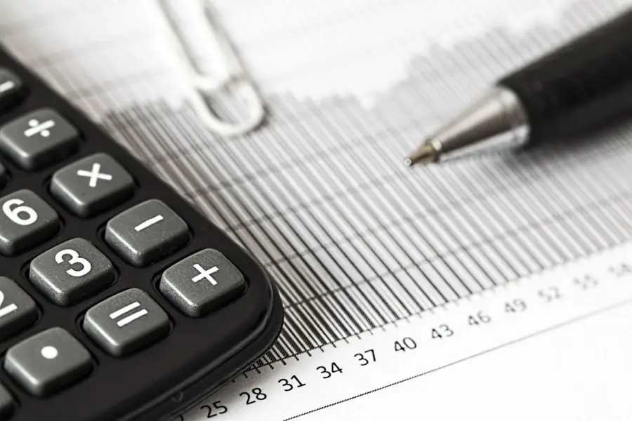 Taschenrechner und Stift liegen auf einer gedruckten Finanzübersicht